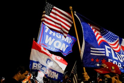 Supporters of former US president Donald Trump wave flags as they gather outside his Mar-a-Lago home after Trump said that FBI agents raided it.