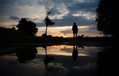 Una mujer pasea a su perro mientras el sol se pone en Ebing, en el sur de Alemania.