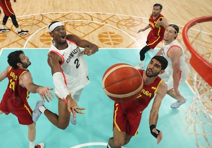 El canadiense Shai Gilgeous-Alexander, en acción ante Alex Abrines y Santi Aldama, con Rudy Fernández en el fondo de la imagen.