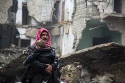 Um homem sírio ao lado de um menino abandona um bairro de Aleppo, em 13 de dezembro