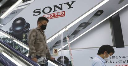 Dos personas pasan junto a una publicidad de Sony en una tienda en Tokio.