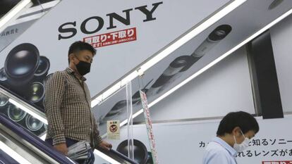 Dos personas pasan junto a una publicidad de Sony en una tienda en Tokio. 