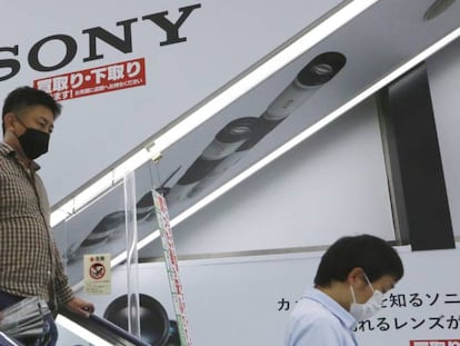 Dos personas pasan junto a una publicidad de Sony en una tienda en Tokio. 