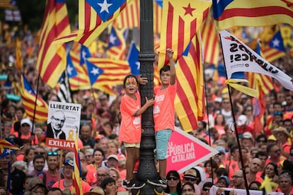 Duas crianças subidas em um poste de luz acompanham a celebração da Diada, o Dia Nacional da Catalunha, neste 11 de setembro de 2018, em Barcelona.