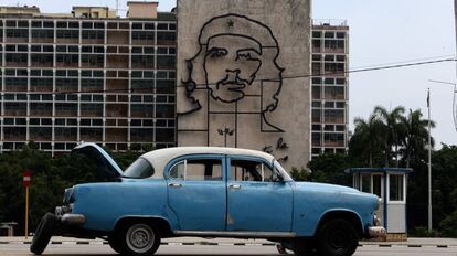 Un automóvil estadounidense clásico averiado frente al Ministerio del Interior de Cuba cuya fachada esta decorada con la imagen del Che.