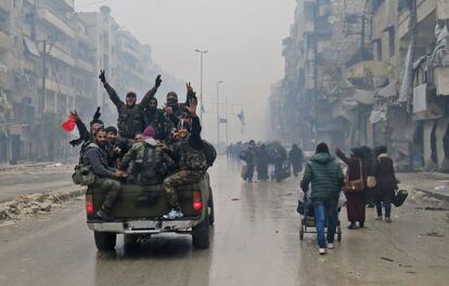 Guerrilleros sirios a favor del régimen gesticulan mientras conducen por el vecindario de Bustan al-Qasr, en el barrio de Fardos de Alepo (Siria), después de que retomaran el control del área que defendían los combatientes rebeldes.