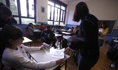 Profesora reparte exámenes entre los alumnos en un colegio público.