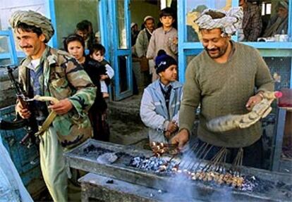 Un afgano prepara pinchos de carne al estilo tradicional ante una casa, en Mazar-i-Sharif.