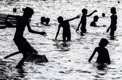 Un grupo de niños juegan en una piscina decorativa que adorna los jardines que rodea la Puerta de la India, en Nueva Delhi.