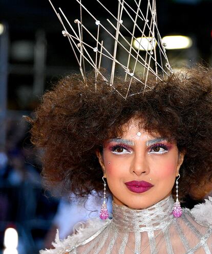 Priyanka Chopra
Además de una impresionante corona y un pelo afro sorprendente, Priyanka Chopra ha acompañado su look de Dior con un increíble maquillaje creado por Pati Dubroff.
Labios y sombra color cereza intenso, máscara de pestañas y cejas en color blanco, eye-liner inferior también blanco y diversos mini cristales dorados repartidos por el rostro.