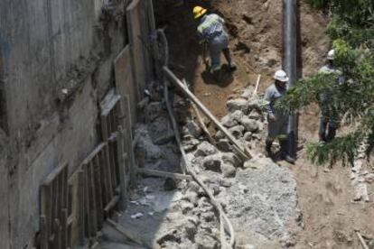 Los obreros restauran uno de los huecos que el agua abrió en el muro.