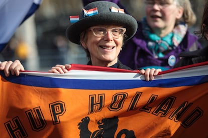 Un manifestante sostiene una bandera de fútbol de Holanda y viste un sombrero con banderas de dicho país durante una manifestación en apoyo de los migrantes en las afueras del Parlamento de Londres, Inglaterra.