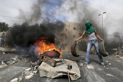Un joven palestino añade neumáticos a un fuego durante enfrentamientos con la policía israelí en Sur Baher, en los suburbios árabes de Jerusalén Este.