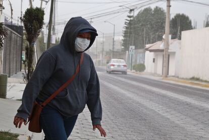 Una mujer usa un cubrebocas para protegerse de la ceniza del volcán en Puebla