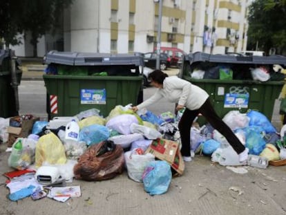 Una mujer deposita una bolsa de basura frente a los contenedores abarrotados en una calle de Jerez.
