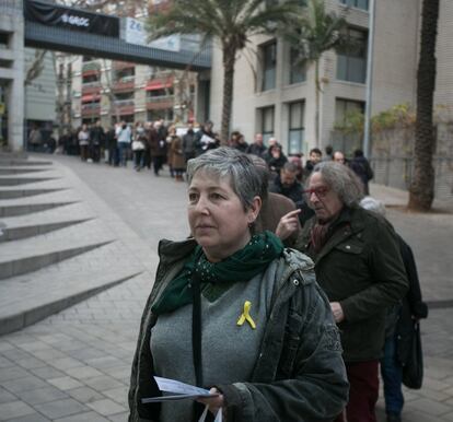 A woman waits to vote wearing a yellow ribbon in support of the jailed Catalan independence leaders.