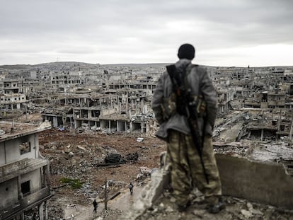 Un miliciano kurdo observa la aldea destruida de Halimce, al este de la ciudad siria de Kobane, en enero de 2015.