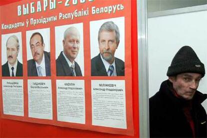 Un ciudadano pasa junto a un cartel de los candidatos presidenciales en un colegio electoral de Navaselle, 40 kilómetros al oeste de Minsk.