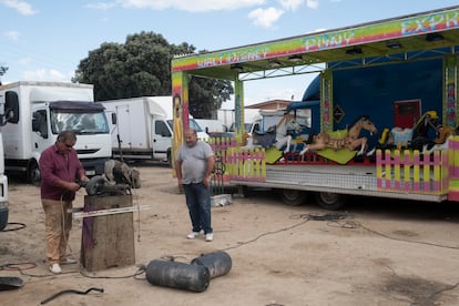 Dos feriantes trabajan reparando las ruedas de una carretilla.