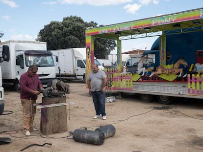 Dos feriantes trabajan reparando las ruedas de una carretilla.