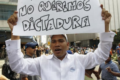 Un hombre muestra un cartel de rechazo a la Ley Habilitante en una protesta a las puertas de la Asamblea venezolana durante la votación de la medida.