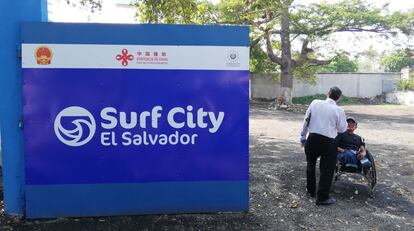 Un par de hombres conversan junto al cartel del proyecto Surf City, el cual cuenta con ayuda financiera de China. Los veteranos de guerra, muchos de ellos desempleados y con miembros mutilados por las minas terrestres, forman parte del pasado que todavía se hace presente en El Salvador.