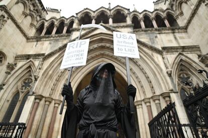 Un manifestante vestido de negro sostiene dos pancartas durante una protesta para pedir la liberación del fundador de WikiLeaks, Julian Assange, frente a los Tribunales Reales de Justicia de Londres (Reino Unido).