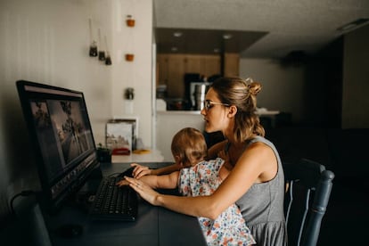 Una madre intenta trabajar con su hija encima.