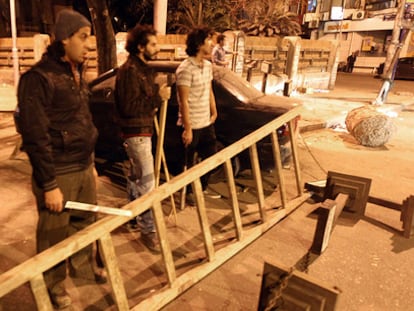 Jóvenes egipcios con palos y bastones bloquean una calle de El Cairo para proteger su propiedad ante los saqueadores