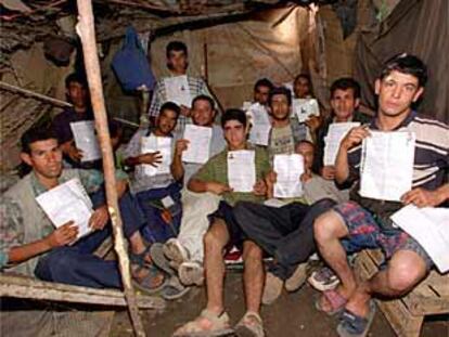 Un grupo de magrebíes muestra, en una chabola de Las Pedroñeras, la solicitud de residencia temporal.