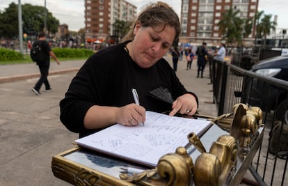 Una mujer deja un mensaje en el libro de condolencias.