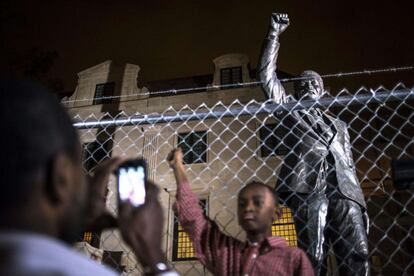 Um pai faz tira foto do seu filho em frente a estátua de Nelson Mandela, situada na embaixada da África do Sul em Washington, 5 de dezembro de 2013.