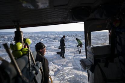 El científico aéreo y oceánico David Holland, de la Universidad de Nueva York (NYU), y el oficial de seguridad de campo Brian Rougeux, reciben ayuda del piloto Martin Norregaard mientras transportan las antenas desde un helicóptero para instalarlas en el Glaciar Helheim, en Groenlandia, el 16 de agosto de 2019. Para Holland y su equipo de la NYU, Groenlandia es donde se escribe el futuro del planeta y actualmente trabajan analizando la fusión alarmante de los glaciares.