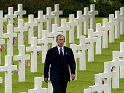 George W. Bush camina por un cementerio de cruces blancas simétricas con banderas estadounidenses durante su visita a Normandía (Francia)