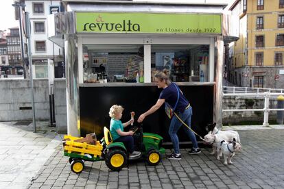 Una mujer compra un helado para su hijo en Llanes (Asturias). Los clientes comentan la actualidad ante un heladero que higieniza el puesto constantemente para evitar contagios o problemas sanitarios. La clientela hace cola con una separación prudente mientras comentan la actualidad del virus.