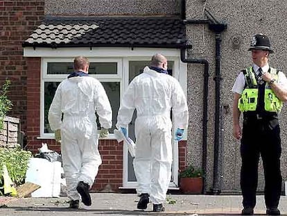 Dos policías con trajes especiales se disponen a entrar en una vivienda sospechosa ayer en Birmingham.