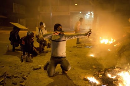 Un grupo de manifestantes tras las barricadas montadas en las calles de Caracas, se enfrentan a la policía durante las protestas contra el Gobierno de Maduro.