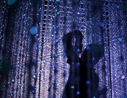 Un visitante toma una fotografa a contraluz mientras interacta con una cortina de luces LED llamada 'Universo de cristal' que forma parte de una instalacin mostrada en la feria 'Future World' en el Museo de las Artes y las Ciencias de Singapur (Singapur).