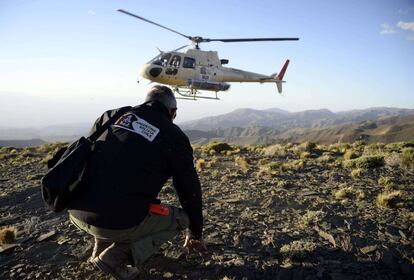 El director del Rally Dakar Etienne Lavigne espera a que un helicóptero transporte a un ciclista rescatado durante la cuarta etapa.