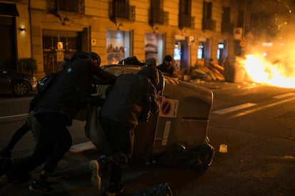 Un grupo de manifestantes mueve un contenedor de basura durante los altercados en el centro de Barcelona.