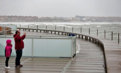 Un hombre toma una fotografía del fuerte oleaje desde el espigón de la Marina del Puerto de Valencia, este sábado.