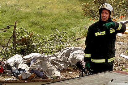 Un bombero, junto a tres de los cadáveres en el lugar del accidente en el que murieron siete personas en la autovía A-1.