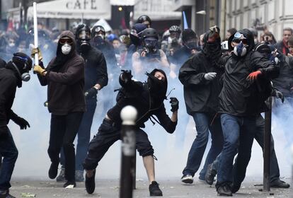 Decenas de miles de personas se han echado a las calles este martes en París en medio de una fuerte presencia policial para protestar contra la reforma laboral que pretende sacar adelante el Gobierno de François Hollande. En la imagen, manifestantes enmascarados lanzan piedras por las protestas laborales, en París.