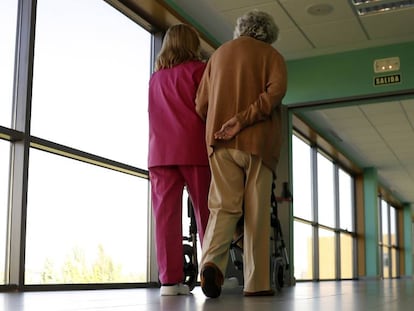 Una treballadora passeja amb una pacient en un centre de referència d'atenció a persones amb alzheimer i demència.