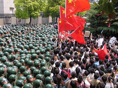 Policías antidisturbios protegen el consulado de Japón en Shanghai de los manifestantes, que portan banderas chinas.