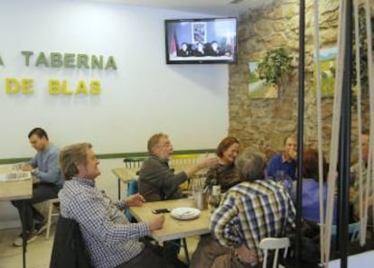 Un grupo de personas conversa en un bar de San Sebastián mientras la televisión informa sobre ETA.