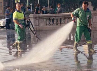 Operarios de servicio municipal de limpieza riegan la calle en Bilbao.