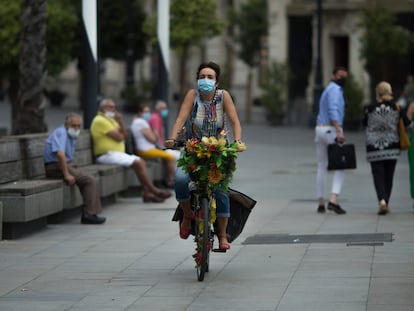 Una mujer con mascarilla pasea en bicicleta por el centro de Sevilla a principios de septiembre.