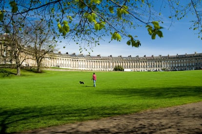 A diferencia de otras grandes explanadas icónicas de Europa, el Royal Crescent <a href="https://elviajero.elpais.com/elviajero/2013/11/07/actualidad/1383832866_665943.html" target="_blank">de la ciudad inglesa de Bath</a> no está rodeado de adoquines o baldosas. Ante el más bello ejemplo de arquitectura georgiana de toda Gran Bretaña se extiende, a cambio, un finísimo manto de césped. Este semicírculo luce 30 magníficos edificios, dispuestos en perfecta simetría, cuyas fachadas adornadas con columnas siguen prácticamente iguales que cuando se construyeron, a finales del siglo XVIII. El museo del edificio n.º 1 muestra cómo son las cosas en el interior de esta 'media luna real'. El Royal Crescent es uno de los rincones más simbólicos de esta ciudad balneario que ya hace más de 2.000 años era un afamado destino turístico por sus beneficiosas aguas termales. Hoy, Bath, patrimonio mundial, atrae no solo por sus vestigios romanos, la mejor arquitectura georgiana y por <a href="https://elpais.com/cultura/2017/07/14/babelia/1500041594_163366.html" target="_blank">la estela de Jane Austen</a>, su habitante más ilustre, sino también por sus calles con tiendas sofisticadas y buenos restaurantes.