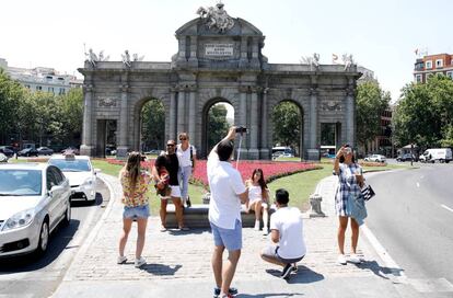 Varios turistas se fotografían ante la puerta de Alcalá, en el centro de Madrid